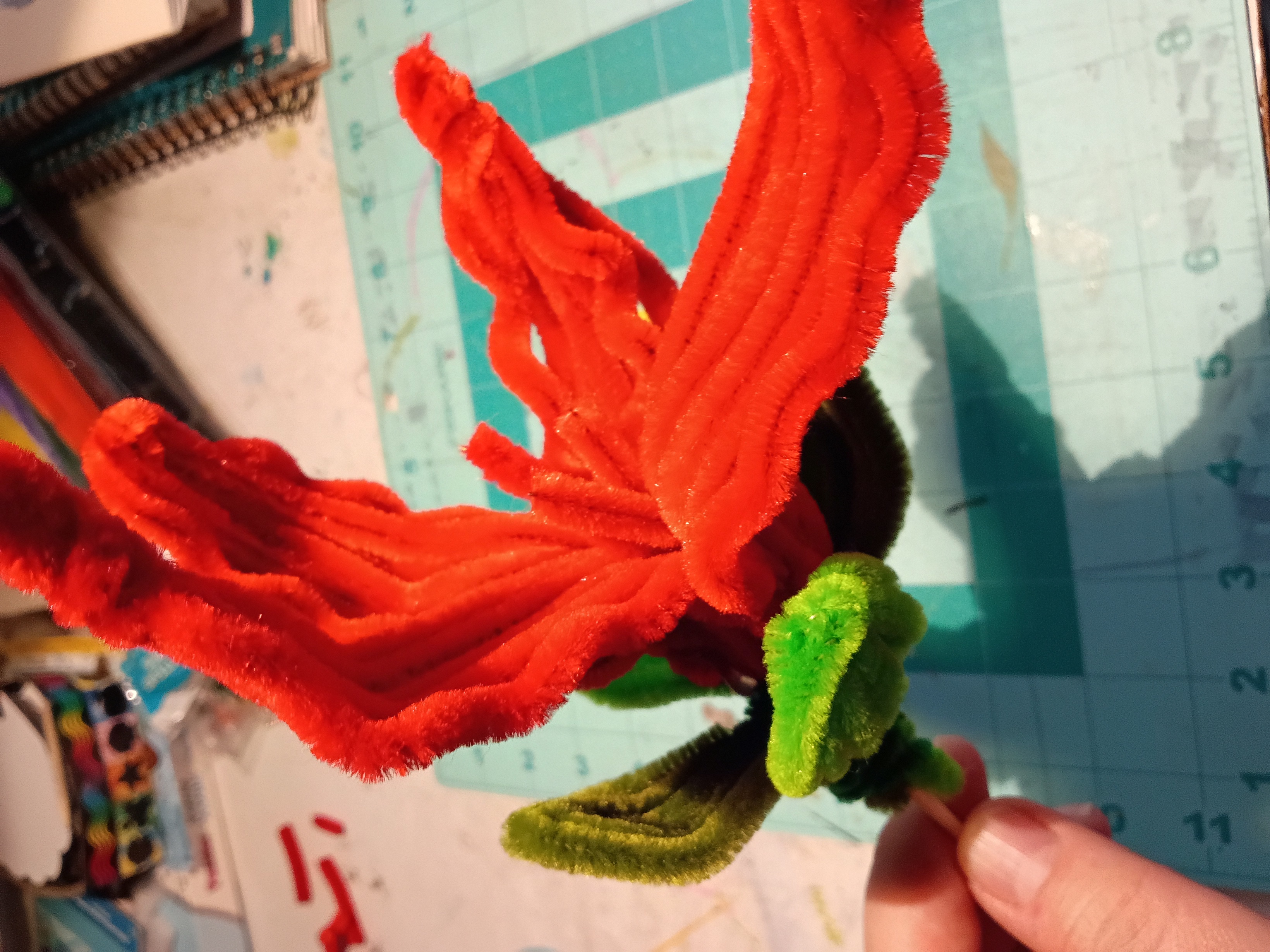 a stack of pipe cleaners formed into petals and leaves glued to a stick
