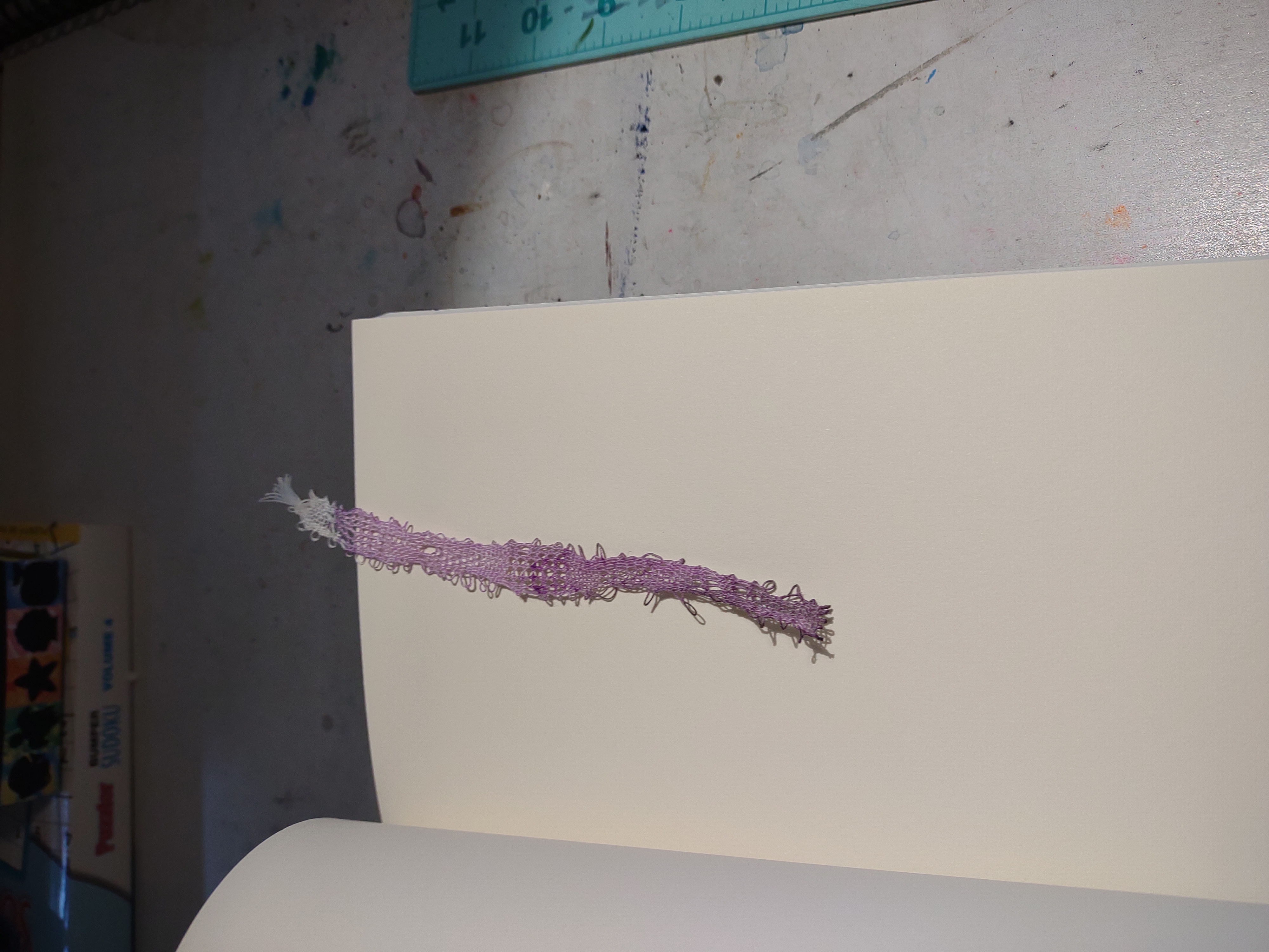 A purple and white lace bookmark laying in the pages of a blank book