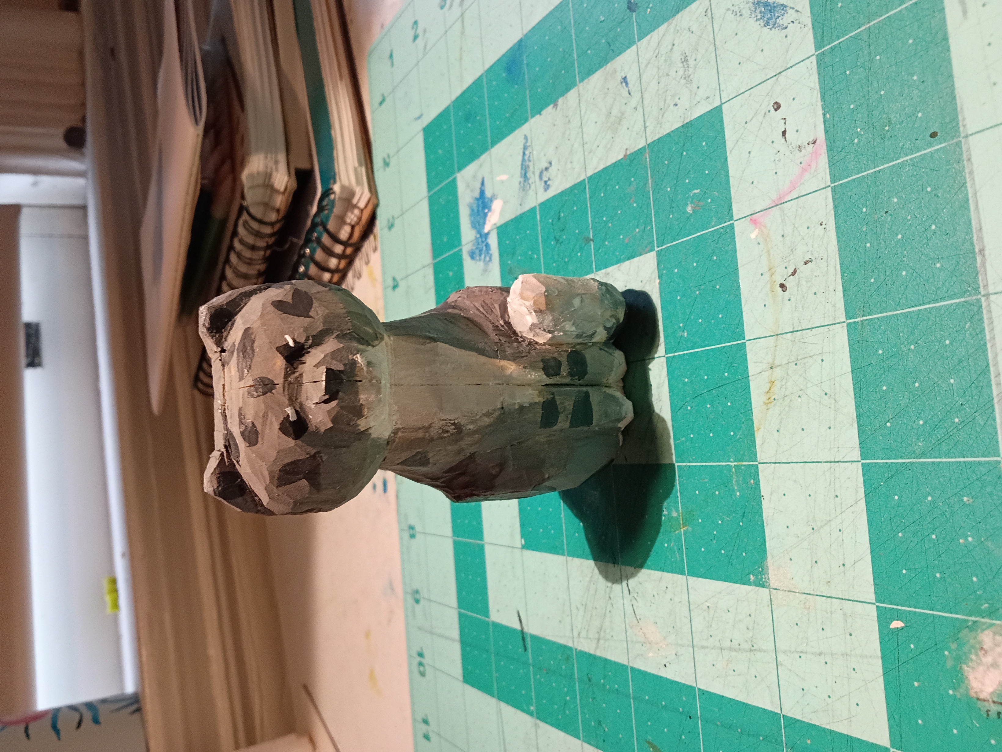 a wooden carved cat painted with grey stripes